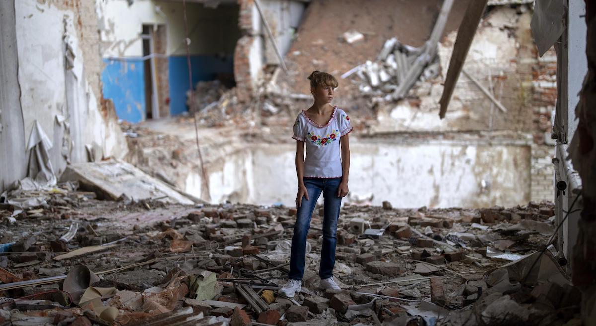 Sofia Klyshnia, 12 anni, in mezzo alle macerie di quella che era la sua classe, esattamente nel punto in cui stava il suo banco del liceo Kotsyubynske bombardato dalle forze russe lo scorso marzo a Chernihiv, in Ucaraina - Foto - AP Photo/Emilio Morenatti/LaPresse