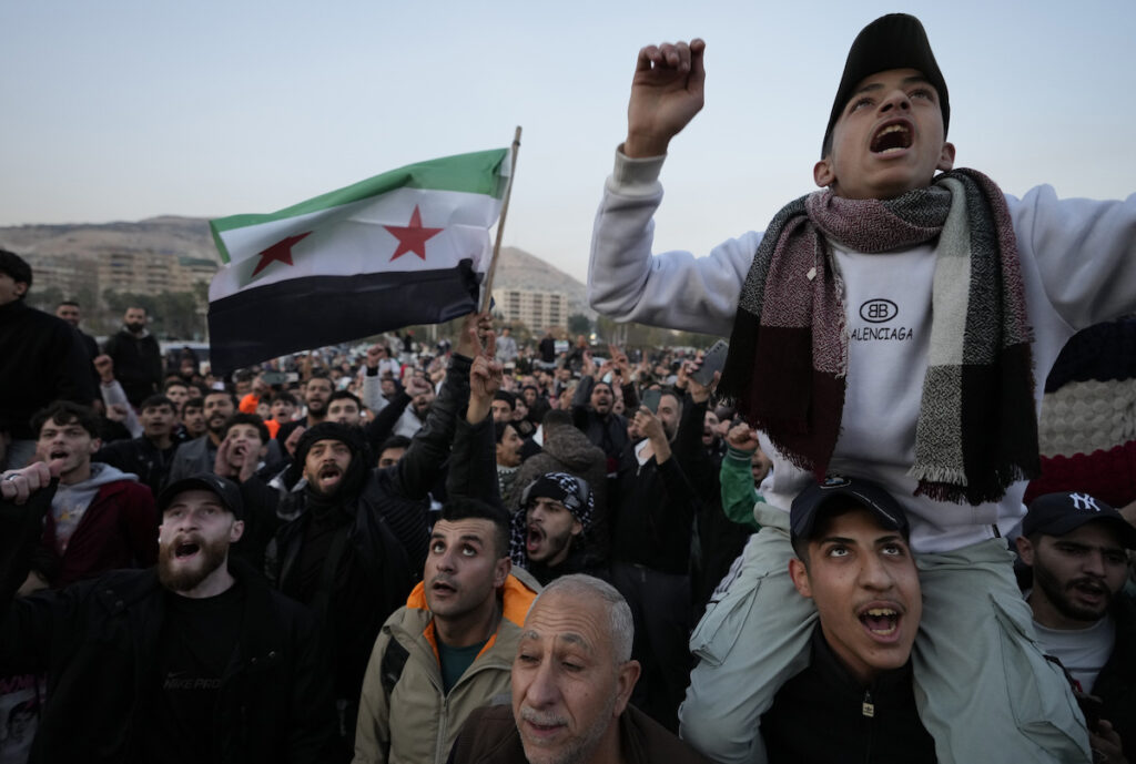 Abitanti di Damasco agitano la bandiera rivoluzionaria dopo la presa della capitale siriana - Foto AP Photo/Hussein Malla/LaPresse Siria