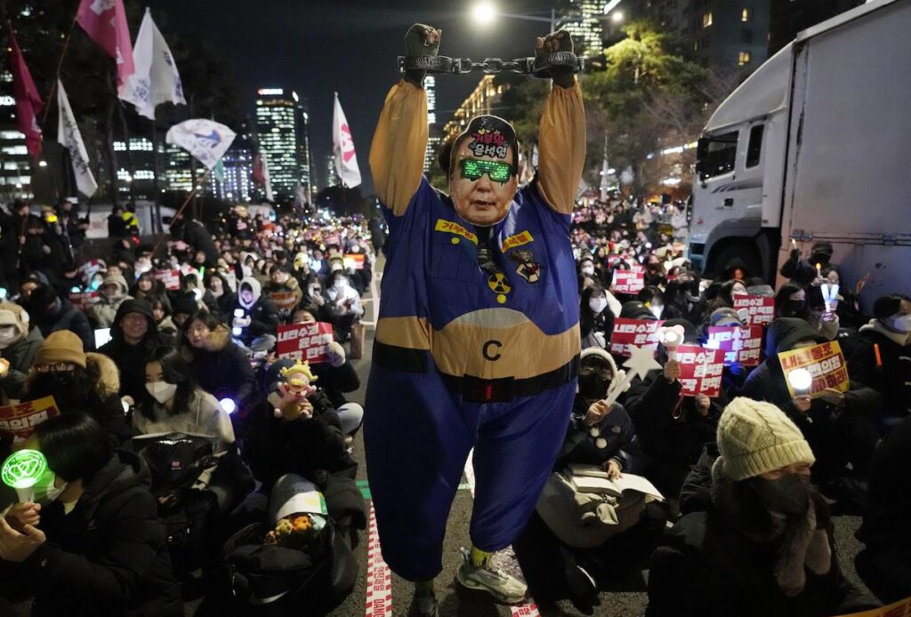 Un manifestante indossa la maschera di Yoon Suk Yeol alla manifestazione per l'impeachment del presidente all'esterno dell'Assemblea nazionale sudcoreana a Seul - Foto AP Photo/Ahnn Young-joon/LaPresse